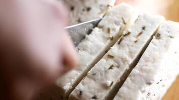 close up of cutting fresh cheese on a chopping background. video