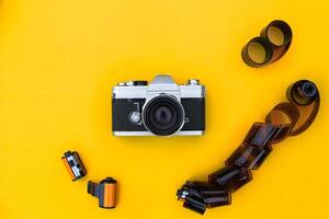 Flat lay vintage camera and film on yellow background photo