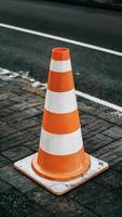 AI generated Striped orange and white road cone on pavement, close up Vertical Mobile Wallpaper photo