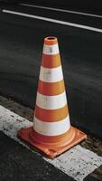 AI generated Striped orange and white road cone on pavement, close up Vertical Mobile Wallpaper photo