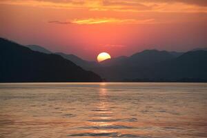 ai generado montañas proporcionar maravilloso fondo a sereno puesta de sol terminado agua foto