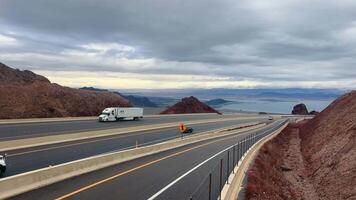 Las Vegas, Nevada, USA - 08 Apr 2024 Scenic Route Overlooking Lake Mead, A highway winds through the desert with a panoramic view of Lake Mead in the distance under a cloudy sky. video