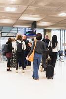 mujer con equipaje en pie en un línea a aeropuerto. foto