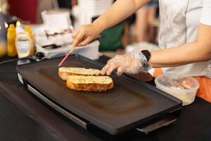 Woman cooking garlic bread with and herbs on iron pan. photo