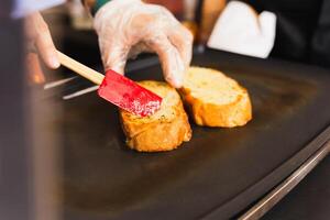 Woman cooking garlic bread with and herbs on iron pan. photo