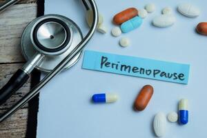 Concept of Perimenopause write on sticky notes isolated on Wooden Table. photo