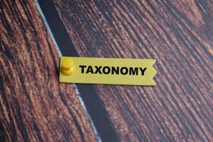 Concept of Taxonomy write on sticky notes isolated on Wooden Table. photo