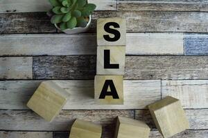 Concept of The wooden Cubes with the word SLA - Service Level Agreement on wooden background. photo