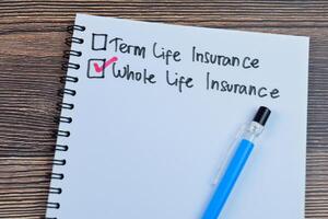 Concept of Whole Life Insurance write on book isolated on Wooden Table. photo