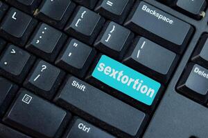 Sextortion write on keyword isolated laptop background photo