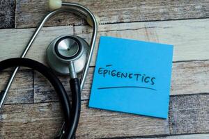 Concept of Epigenetics write on sticky notes isolated on Wooden Table. photo
