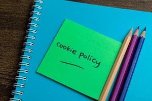 Concept of Cookie Policy write on sticky notes isolated on Wooden Table. photo