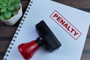 Red Handle Rubber Stamper and Penalty text above book isolated on wooden background photo