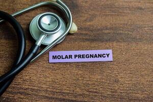 Concept of Molar Pregnancy write on sticky notes isolated on Wooden Table. photo