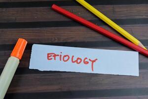 Concept of Etiology write on sticky notes isolated on Wooden Table. photo