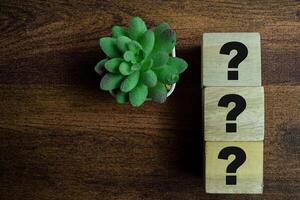 Concept of The wooden Cubes with the word Three question marks on wooden background. photo