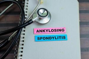 Concept of Ankylosing Spondylitis write on sticky notes with stethoscope isolated on Wooden Table. photo