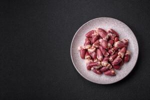 Raw chicken hearts with salt, spices and herbs photo