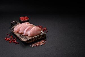 Slices of raw chicken or turkey fillet with salt, spices and herbs photo