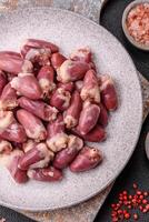 Raw chicken hearts with salt, spices and herbs photo