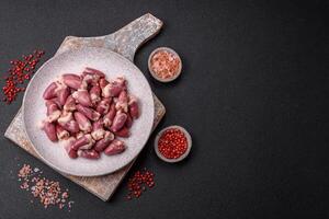 Raw chicken hearts with salt, spices and herbs photo