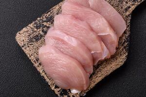 Slices of raw chicken or turkey fillet with salt, spices and herbs photo