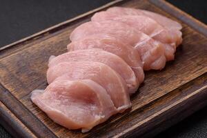 Slices of raw chicken or turkey fillet with salt, spices and herbs photo