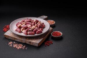 Raw chicken hearts with salt, spices and herbs photo