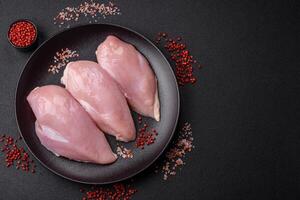 Fresh chicken fillet on a dark concrete table with spices and herbs photo