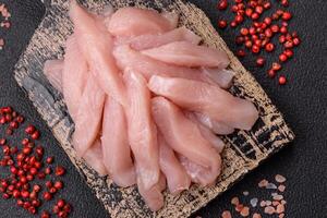Slices of raw chicken or turkey fillet with salt, spices and herbs photo