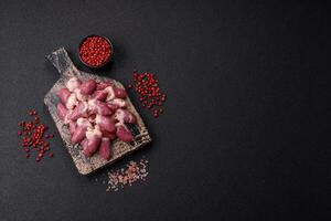 Raw chicken hearts with salt, spices and herbs photo