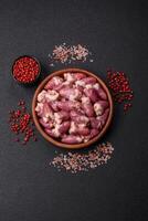 Raw chicken hearts with salt, spices and herbs photo