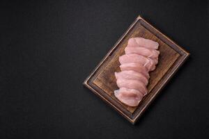 Slices of raw chicken or turkey fillet with salt, spices and herbs photo