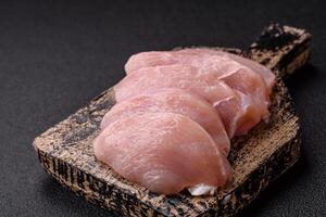 Slices of raw chicken or turkey fillet with salt, spices and herbs photo