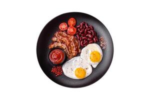 English breakfast with fried eggs, bacon, beans, tomatoes, spices and herbs photo