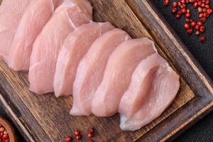 Slices of raw chicken or turkey fillet with salt, spices and herbs photo