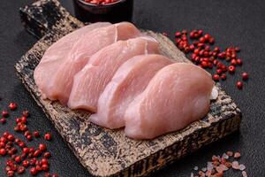 Slices of raw chicken or turkey fillet with salt, spices and herbs photo