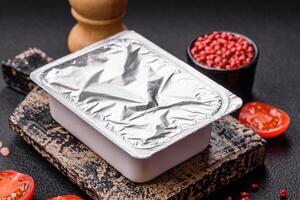 Rectangular plastic box with yogurt or cheese hermetically sealed with a foil lid photo