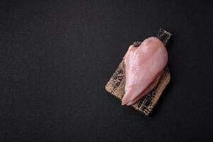 Fresh chicken fillet on a dark concrete table with spices and herbs photo