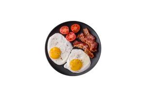 English breakfast with fried eggs, bacon, beans, tomatoes, spices and herbs photo