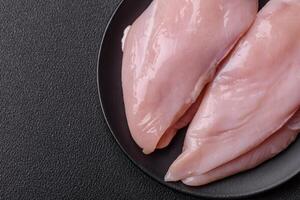 Fresh chicken fillet on a dark concrete table with spices and herbs photo