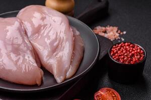 Fresh chicken fillet on a dark concrete table with spices and herbs photo