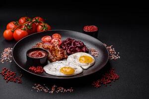English breakfast with fried eggs, bacon, beans, tomatoes, spices and herbs photo
