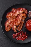 Delicious fresh fried bacon with salt and spices on a dark background photo