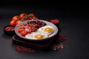 English breakfast with fried eggs, bacon, beans, tomatoes, spices and herbs photo