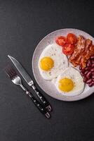 English breakfast with fried eggs, bacon, beans, tomatoes, spices and herbs photo