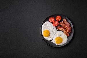 English breakfast with fried eggs, bacon, beans, tomatoes, spices and herbs photo