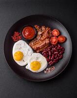 desayuno inglés con huevos fritos, tocino, frijoles, tomates, especias y hierbas foto