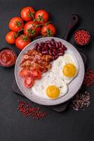 English breakfast with fried eggs, bacon, beans, tomatoes, spices and herbs photo
