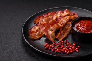 Delicious fresh fried bacon with salt and spices on a dark background photo